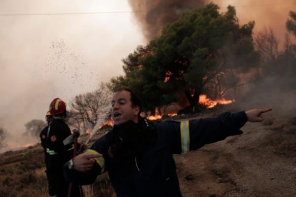 epa10813671 Fire Lieutenant Argyris Makaro<em></em>nas directs his crew while battling flames of a wildfire at the area of Fyli near Athens, Greece, 22 August 2023. A wildfire is in progress in Fyli, west Attica region. So far, 26 firefighters with 13 vehicles are operating, while air forces have also been mobilized. EPA/KOSTAS TSIRONIS