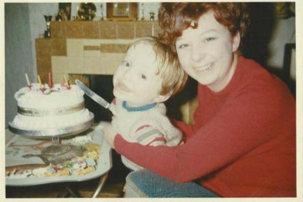 Kevin Do<em></em>nnellon when he was little, with his mum, who his helping him cut a birthday cake - both smiling at the camera.